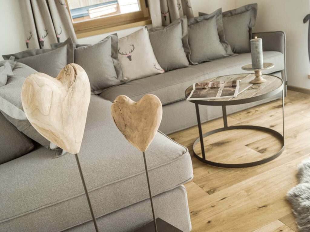 Tischlerei Trixl - Wohnbereich mit Holzboden, Sofa und Deko aus Holz, Hotel Chalets Großlehen